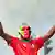 A protester wearing a mask in the colors of the Kenyan flag raises his arms