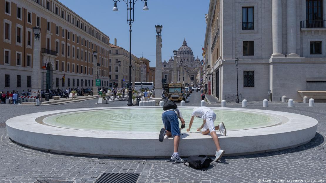 Turistas en Roma, frente a la Ciudad del Vaticano, refrescándose en una fuente. 