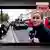 Una periodista reporta desde el centro de Londres ante un desfile de tanques. La imagen fue generada con IA.