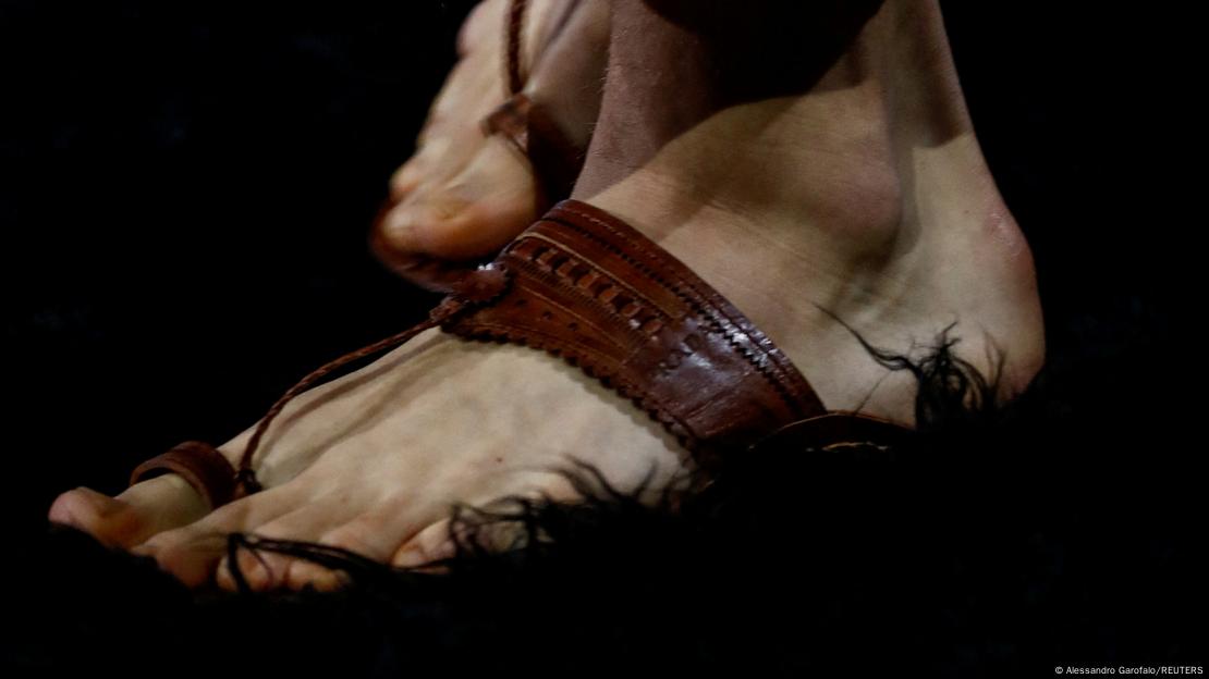 A close-up of a person's foot wearing an open-toe leather sandal.