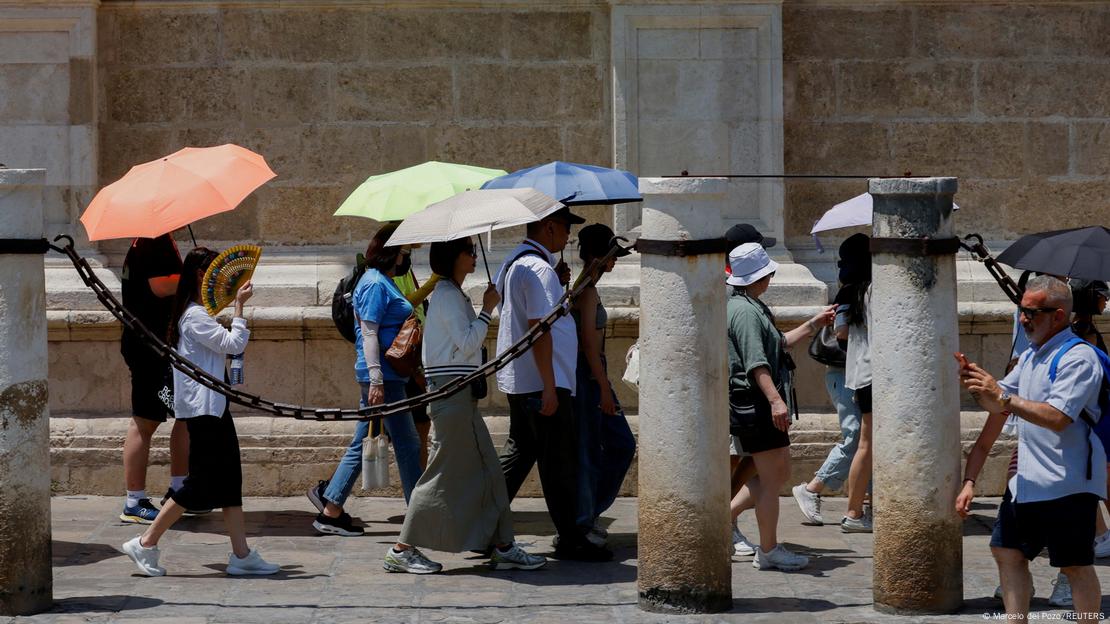 Un grupo de turistas se protegen con sombrillas de la primera ola de calor del año en Sevilla, España (29.06.2025)