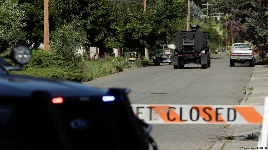 Absperrband über eine Straße gespannt, davor und dahinter je ein gepanzertes Fahrzeug 