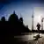 A runner in front of the Berlin Cathedral and TV tower, with the sun bright in the sky