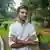বাংলাদেশের অন্তর্বর্তীকালীন সরকারের উপদেষ্টা আসিফ মাহমুদকে দেখা যাচ্ছে একটি বাগানে দাঁড়িয়ে থাকতে৷
