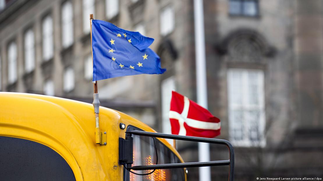 Bandeiras da UE e da Dinamarca colocadas na parte da frente de um ônibus amarelo