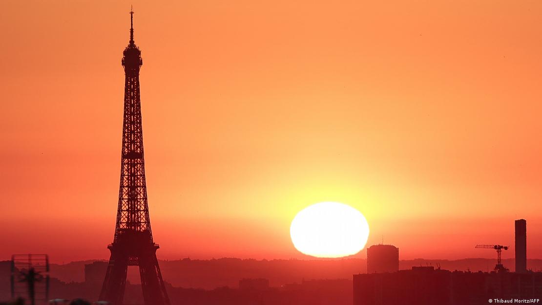 Sol forte em paisagem onde se vê a Torre Eiffel