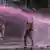 Image of a protester holding the Kenyan flag being sprayed with a pink substance