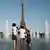 Pessoas se refrescam em fonte pública em frente à torre Eiffel em Paris