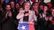 La candidata oficialista se lleva sonriente la mano al corazón desde un atril con la bandera chilena. La candidata oficialista se lleva sonriente la mano al corazón desde un atril con la bandera chilena.