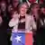 La candidata oficialista se lleva sonriente la mano al corazón desde un atril con la bandera chilena.