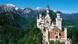 Das pittoreske Schloss Neuschwanstein thront über dem Alpenrand vor einer Bergkulisse Das pittoreske Schloss Neuschwanstein thront über dem Alpenrand vor einer Bergkulisse