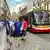 Three men stand on the road in Prague next to an unpowered tram