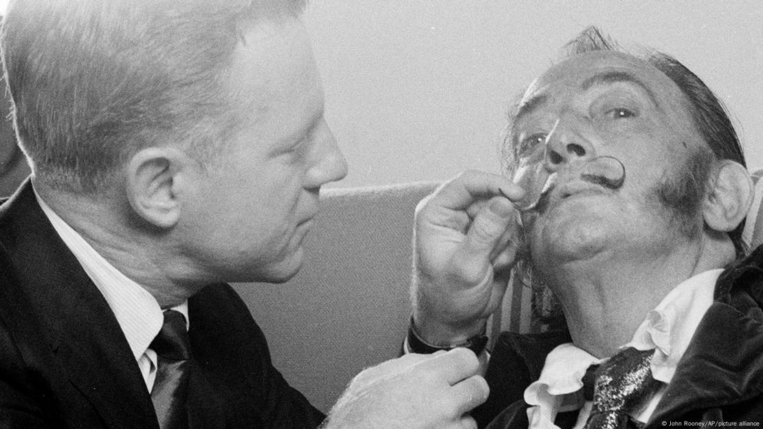 El lanzador de los New York Yankees, Whitey Ford, jugueteó con el famoso bigote de Salvador Dalí durante el rodaje de un comercial para una aerolínea en Nueva York el 6 de febrero de 1969. El lanzador de los New York Yankees, Whitey Ford, jugueteó con el famoso bigote de Salvador Dalí durante el rodaje de un comercial para una aerolínea en Nueva York el 6 de febrero de 1969.