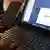A woman uses a smartphone in front of a laptop