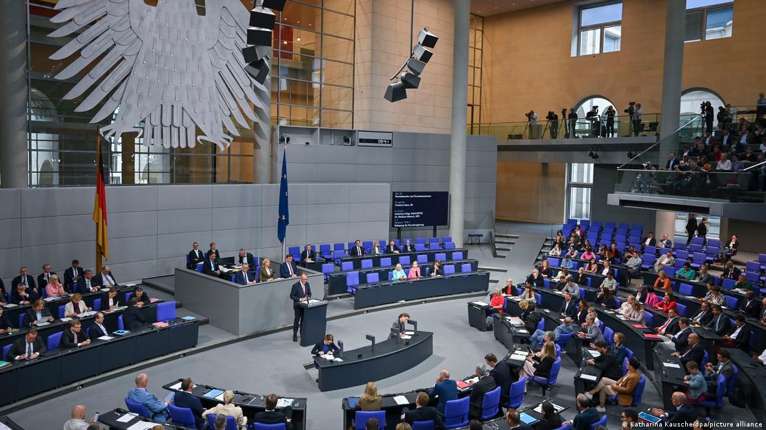 Deutschland Berlin 2025 | Bundeskanzler Friedrich Merz steht in der Generaldebatte zum Haushalt am Rednerpult. Das Foto zeigt einen Blick in das Plenum es Bundestags mit gut gefüllten Sitzreihen.