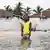 Ein Mann steht im Wasser vor zwei Häusern, deren Grundmauern schon fast vom Meeresspiegel erreicht ist - Sierra Leone Nyangai Island 2025