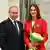 Vladimir Putin stands next to fencer Sofya Velikaya, who holds a bouquet of flowers and wears a medal around her neck