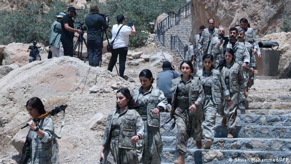 PKK militanları Süleymaniye'deki silah bırakma töreninde silahlarını yakmak üzere tören alanına gelirken PKK militanları Süleymaniye'deki silah bırakma töreninde silahlarını yakmak üzere tören alanına gelirken