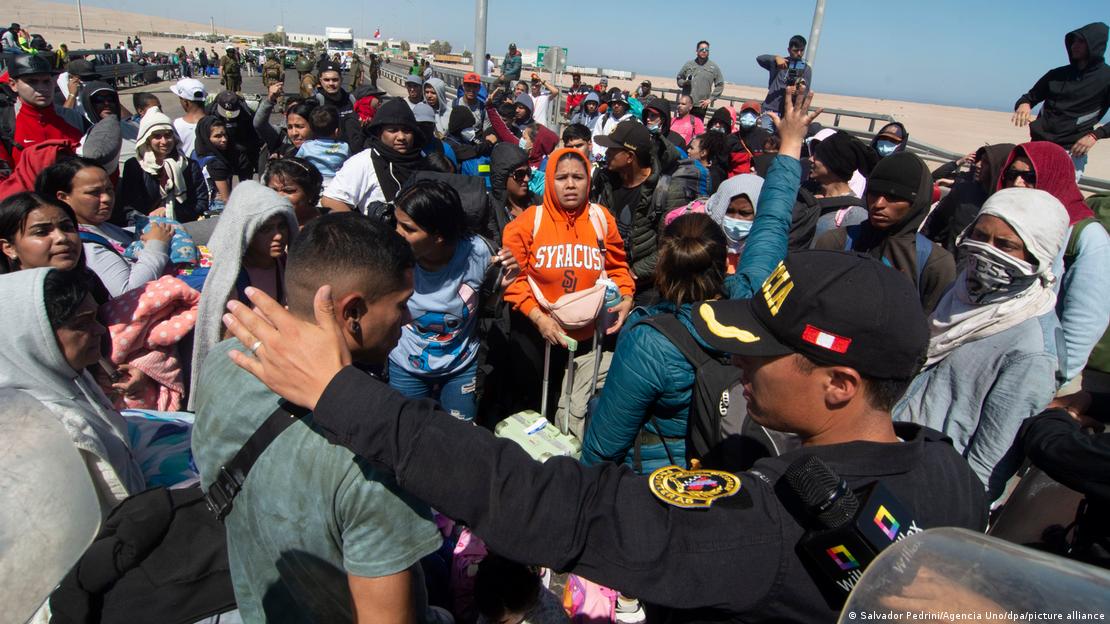 Migrantes en la frontera entre Chile y Perú, junto a un policía peruano. (Archivo).