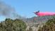 El avión, volando a baja altura, descarga agua tintada de rojo sobre una zona boscosa humeante, el pasado 10 de julio, seis días después de iniciarse el incendio. El avión, volando a baja altura, descarga agua tintada de rojo sobre una zona boscosa humeante, el pasado 10 de julio, seis días después de iniciarse el incendio.