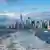 Blick auf viele Wolkenkratzer unterschiedlicher Größe von einem Schiff aus, dazwischen Wasser (New York)