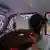 Mujer con abanico en el asiento delantero de un auto.
