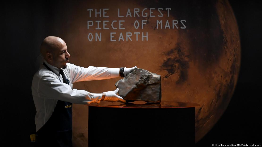 Un técnico de la casa de subastas Sotheby's coloca la roca marciana en una superficie para su exposición.