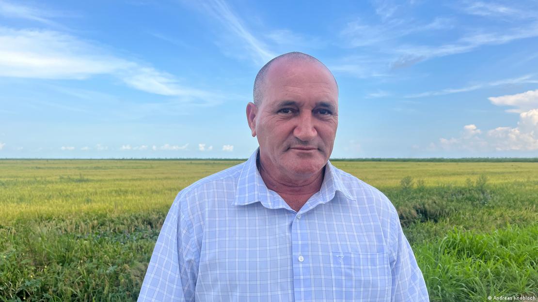 Ariel García Pérez, director general de la Empresa Agroindustrial de Granos, y un campo de arroz detrás.