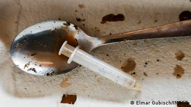Image 10: A metal spoon filled with brown liquid heroin and a syringe.