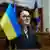 Die neu gewählte Ministerpräsidentin der Ukraine Julia Swyrydenko spricht im Parlament, zu sehen sind Mikrofone des Rednerpults und eine blau-gelbe ukrainische Fahne im Vordergrund