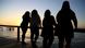 Mulheres com diferentes corpos, magros e gordos, assistem ao pôr do sol em frente a uma baía Mulheres com diferentes corpos, magros e gordos, assistem ao pôr do sol em frente a uma baía