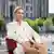 AfD lideri Alice Weidel ile söyleşi açık havada yapıldı. Weidel bir sandalyede oturuyor arkasında bina ve bir alan görülüyor.