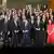 más de 60 hombres con traje y 2 mujeres posan para foto grupal