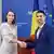O femeie şi un bărbat îşi strâng mâna pe fundalul unor steaguri: Oana Ţoiu şi Mihai Popsoi