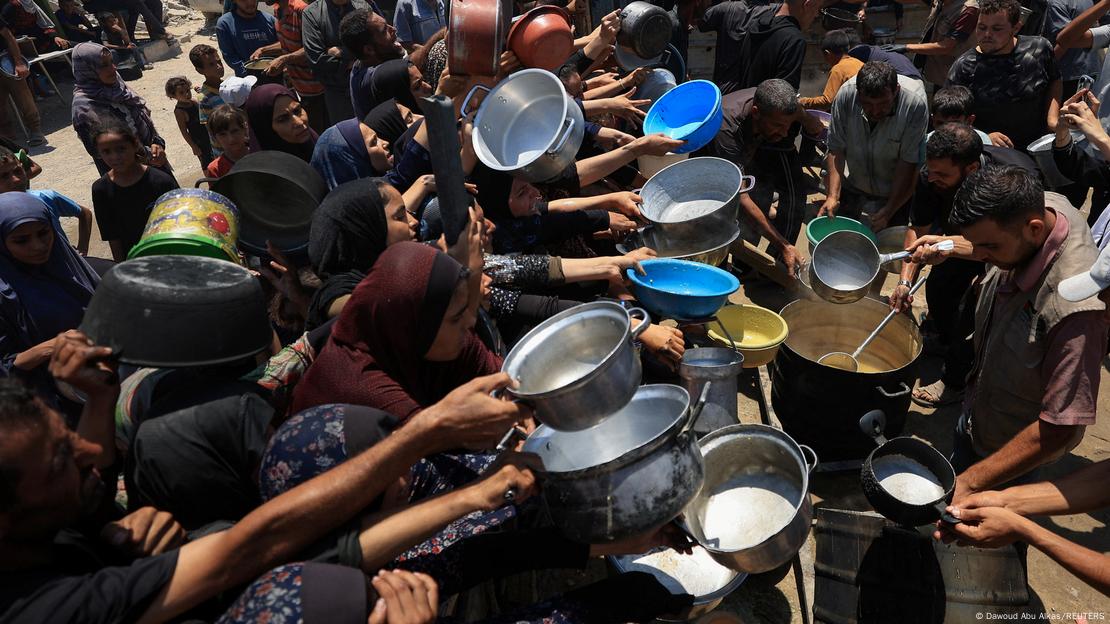 Cientos de palestinos buscan recibir alimentos con recipientes en sus manos, en una cocina de apoyo alimentario la Franja de Gaza. Cientos de palestinos buscan recibir alimentos con recipientes en sus manos, en una cocina de apoyo alimentario la Franja de Gaza.