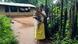 Sukli Oyam carrying the daughter of her son Ramesh in front of her house