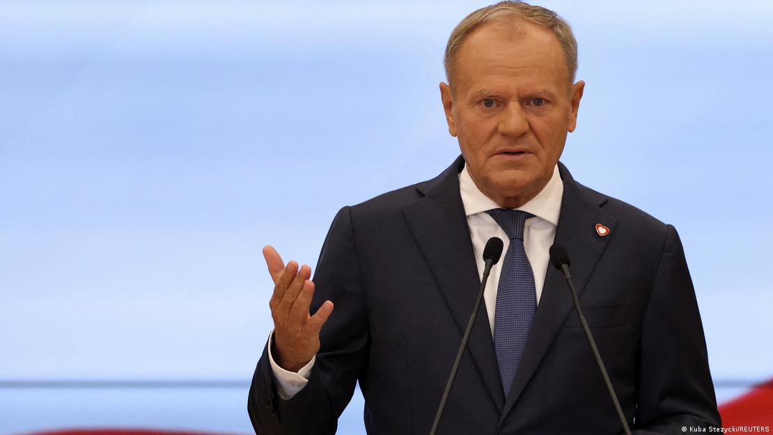 Ein Mann, der polnische Premier Donald Tusk, steht hinter zwei Mikrofonen und gestikuliert, während er spricht
