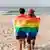 Lesbian couple at the beach with a rainbow flag