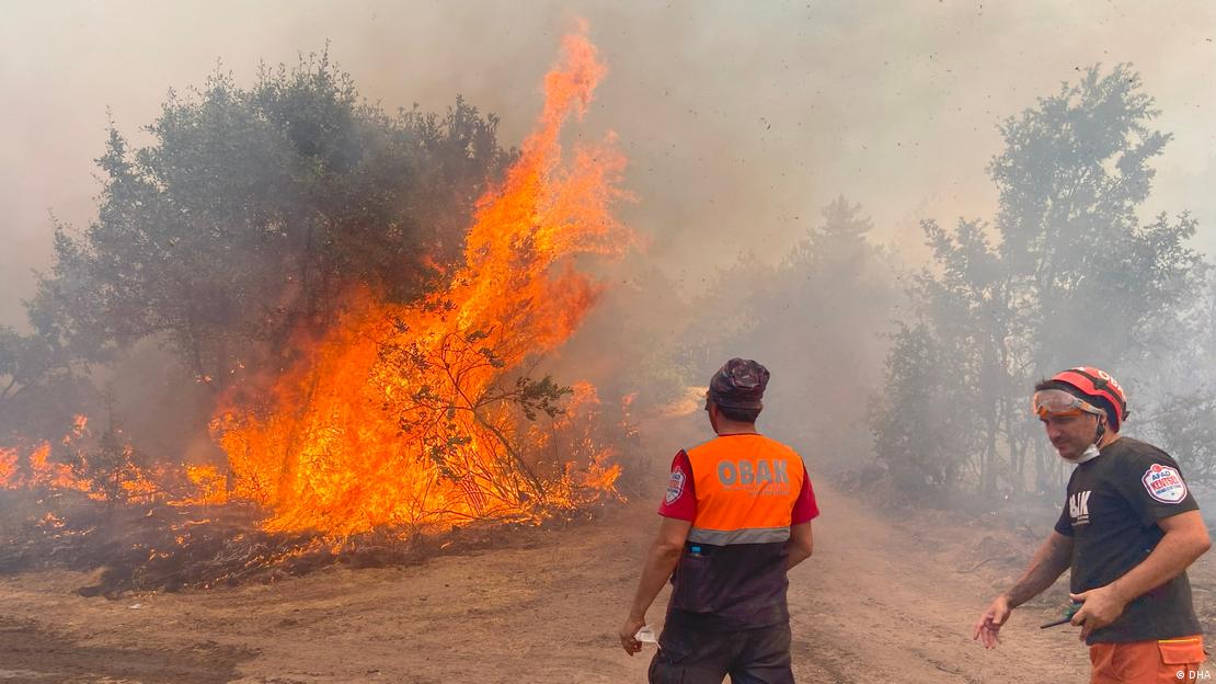 Un incendio en Eskisehir, Turquía, que le costó la vida a 10 personas. Se ven llamas en una superficie extensa con árboles y dos bomberos. Un incendio en Eskisehir, Turquía, que le costó la vida a 10 personas. Se ven llamas en una superficie extensa con árboles y dos bomberos.