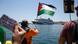 A protester waves a Palestinian flag as people demonstrates in front of a cruise ship carrying Israeli tourists and trying to approach the Aegean Sea island of Syros, Greece. A protester waves a Palestinian flag as people demonstrates in front of a cruise ship carrying Israeli tourists and trying to approach the Aegean Sea island of Syros, Greece.