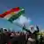 A Syrian Kurdish woman dances and holds the Kurdish flag
