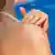 A woman applies sunscreen to her shoulders