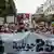 Protests wave banners again Tunisia's President Kais Saied on 25 July, 2025 as they walk down a street.