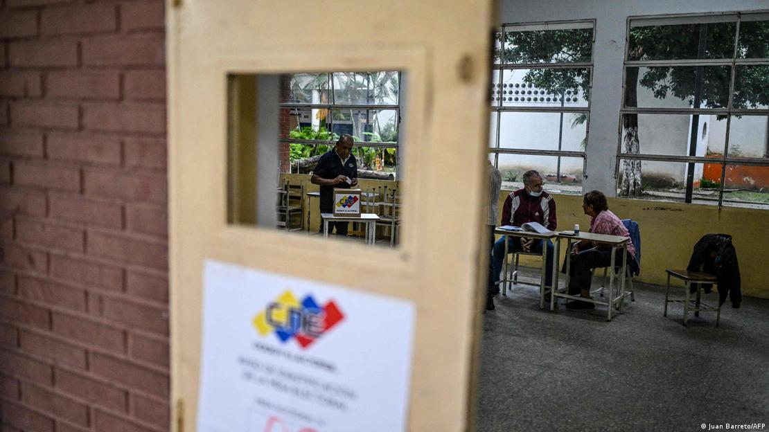 Centro electoral con personas sentadas en las mesas de votación, pero sin electores.