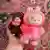 A hand holds one small brown Monchichi doll next to a larger pink fury Labubu doll.