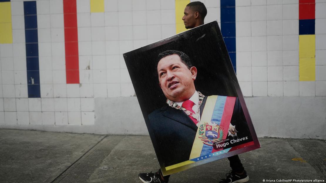 Homem segura cartaz com foto de Hugo Chávez.