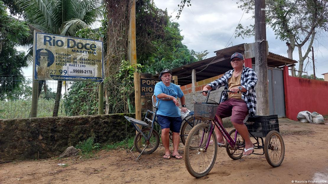 Dois homens idosos em bicicletas em uma rua de terra