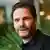 Daniel Brühl mit Bart und schwarzem Hemd blickt in die Kamera