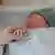 A mother's hand holding the hand of her sleeping newborn