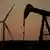 A pumpjack operates in the foreground while a wind turbine at the Buckeye Wind Energy wind farm rises in the distance in Kansas